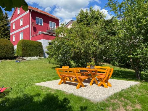 a picnic table and bench in front of a red house at Ferienhaus SweetHome - eingezäunter Garten - 3 Hunde willkommen - ruhige Sackgasse in Bad Sachsa