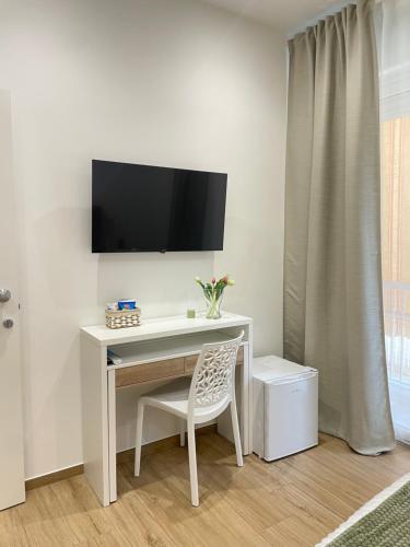 ein Schreibtisch mit Stuhl und ein Fernseher an der Wand in der Unterkunft Marylen in Gela