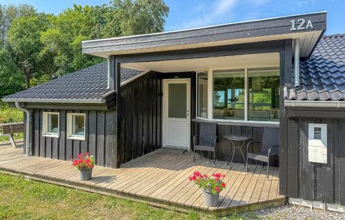 a black house with a deck with flowers on it at Lovely Home In Ebeltoft With Sauna in Ebeltoft