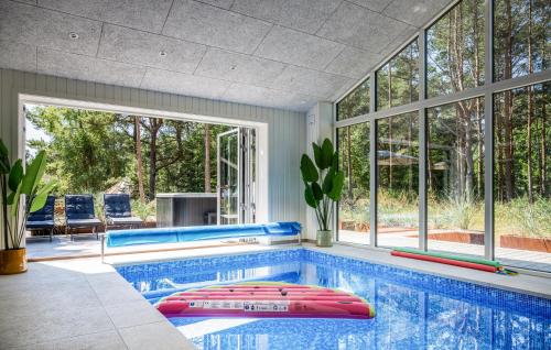 a swimming pool in a house with a room with windows at Nice Home In Nexø With Sauna in Neksø