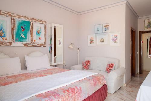 a bedroom with a bed and two white chairs at Apartments Gina y Vista Oceano in Puerto del Carmen
