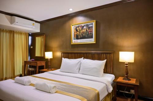 a hotel room with two beds and two lamps at The Victory Residences Bangkok in Bangkok