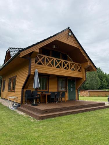 a house with a deck with a table and chairs at Piliakalnio Sodyba in Ilgininkai