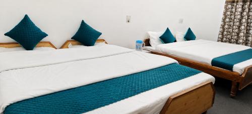 two beds in a room with blue pillows at Hotel Dharali Nature In Dharali in Gangnāni