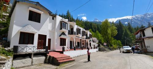 a person standing in front of a building on a street at Hotel Dharali Nature In Dharali in Gangnāni