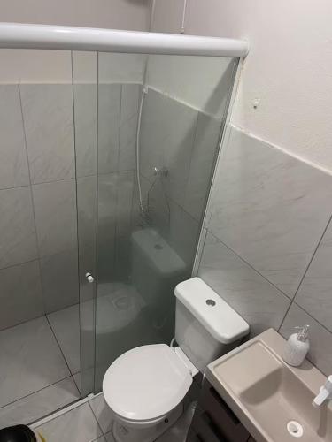 a white bathroom with a toilet and a sink at Pousada Coral in Osório
