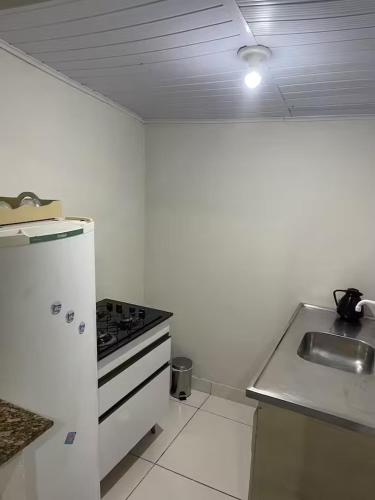 a white kitchen with a stove and a sink at Pousada Coral in Osório