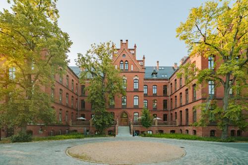 a large red brick building with trees in front of it at ARCHE Klasztor Wrocław in Wrocław