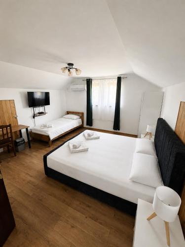 a bedroom with a large white bed and a tv at La Luca in Maliuc