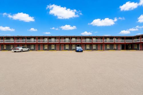 a large building with two cars parked in a parking lot at Valley Motel Corpus Christi Near Airport I 37 in Corpus Christi