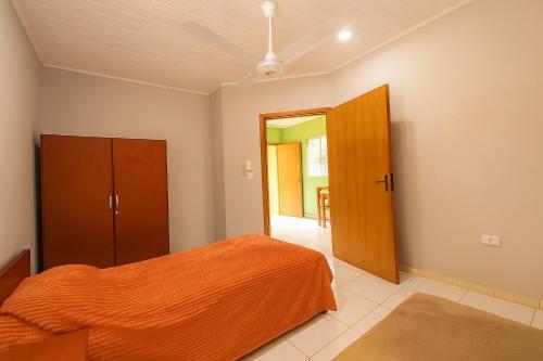 a bedroom with an orange bed and a open door at Complejo de Apartamentos parque naturaleza in Encarnación