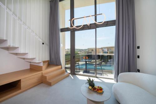 a living room with a white couch and a large window at Ventale Island Breeze Resort in Georgioupolis