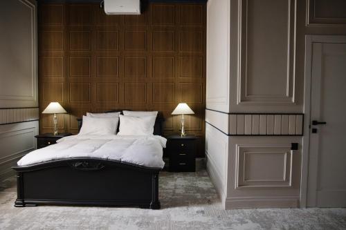 a bedroom with a bed with two night stands and two lamps at Lumen in Kostanay