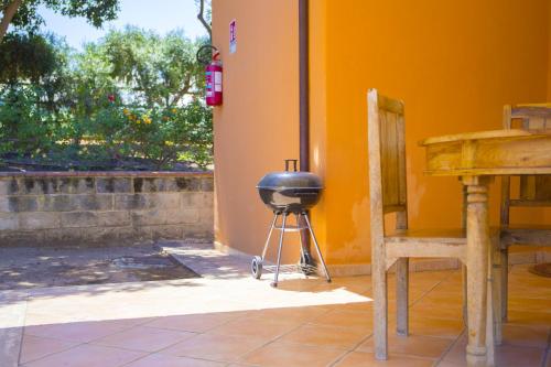 a grill sitting on a stand next to a wall at Solemar Sicilia - Le Casette Di Calzata in Campofelice di Roccella