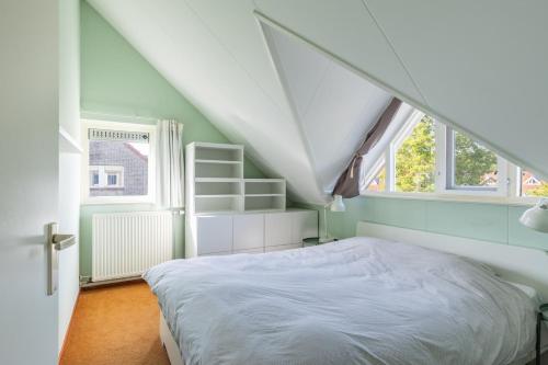 a bedroom with a white bed and two windows at Cozy Waterfront Getaway for a Perfect Holiday in Langweer