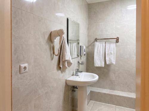 a white bathroom with a sink and a shower at Taugul Hotel in Almaty