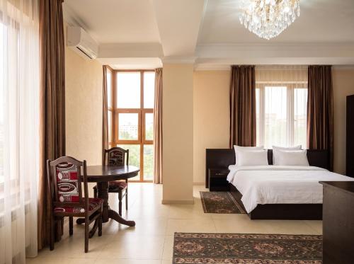 a bedroom with a bed and a desk and a table at Taugul Hotel in Almaty