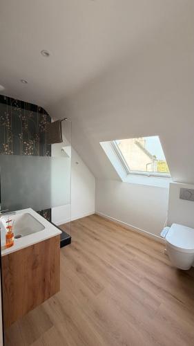 a bathroom with a sink and a toilet and a skylight at Maison de la plage - Dossen Santec - Réservations à la semaine, de week-ends en week-ends in Santec