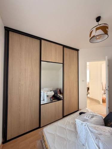 a bedroom with a large wooden closet with a mirror at Maison de la plage - Dossen Santec - Réservations à la semaine, de week-ends en week-ends in Santec