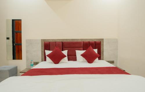 a bedroom with a white bed with red pillows at Hotel Galaxy 700 - A Luxury Hotel Near KhatuShyamJi Temple in Khātu