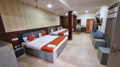 a bedroom with two beds with orange pillows at Sarovar Palace in Prayagraj