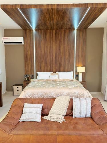 a large bed with a brown couch in a bedroom at Roses Villa at Elysium Home in Dodoma