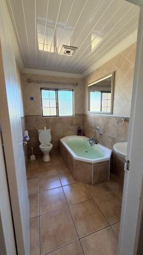 a bathroom with a tub and a toilet and a sink at Trendy Tranquility in Secunda