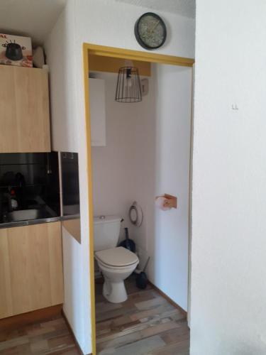 a bathroom with a toilet and a clock on the wall at Studio montagne in Mijoux