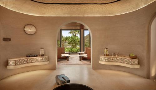 a living room with an archway and a living room with a table at Six Senses AMAALA in Amala