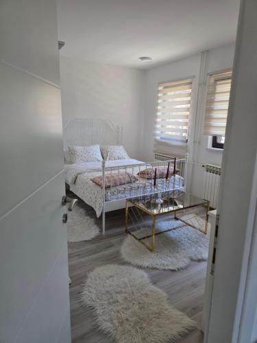 a white bedroom with a bed and a table at Riverside Residence Apartment in Travnik