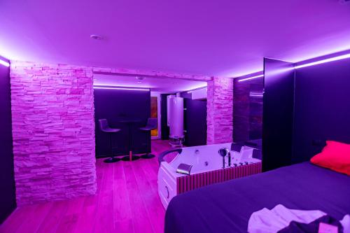 a bedroom with a bed and a tub and a stone wall at Cristal Room in Rochefort