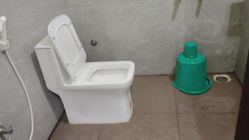 a bathroom with a toilet and a green trash can at RK Residency in Tirupati