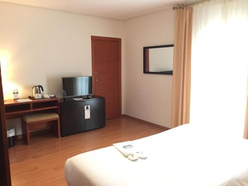 
a hotel room with a bed, desk and television at TRH Ciudad de Baeza in Baeza
