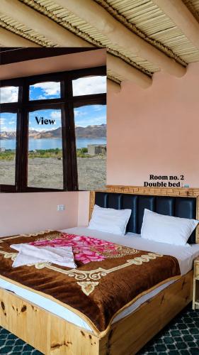 a large bed in a room with a large window at Deachen Khangsar in Spangmik