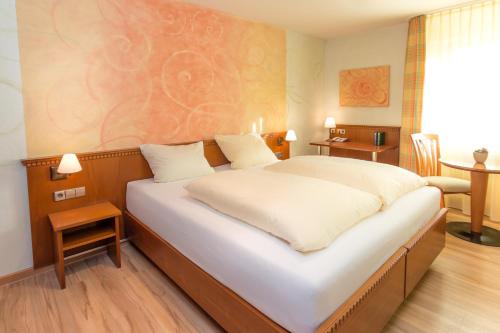 a bedroom with a large white bed in a room at Wirthshof Hotel & Chalets in Markdorf