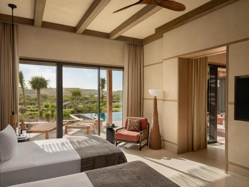 a hotel room with two beds and a balcony at Six Senses AMAALA in Amala