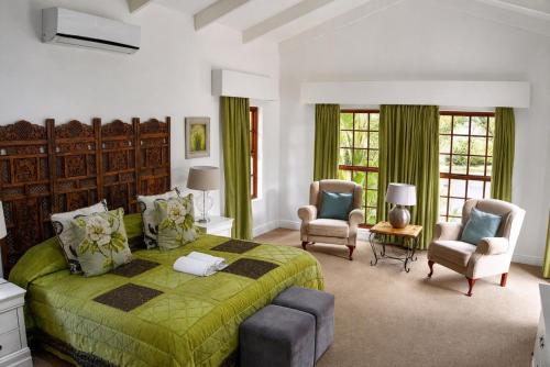 a bedroom with a green bed and two chairs at Val d'Or Estate in Franschhoek