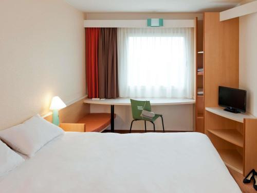 ein Hotelzimmer mit Bett, Schreibtisch und Fenster in der Unterkunft Ibis Ulm City in Ulm