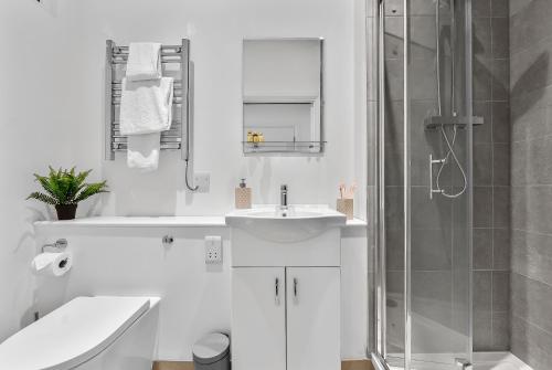 a white bathroom with a sink and a shower at Newly Reopened, Modern Flat Central Location in Staines