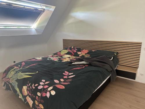 a bed with a black comforter and a window at Maison de Corinne in Sarzeau