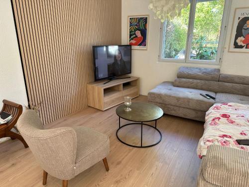 a living room with a tv and a couch and a table at Maison de Corinne in Sarzeau