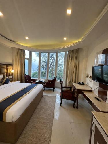 a hotel room with a bed and a television at The Zinnia Castle- Dharamshala # Centrally Heated & Air Cooled # Premium Rooms # Lift # Bar # Terrace # Big Parking # Near market # Top Rated # Property of the year in Dharamshala