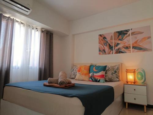 a bedroom with a bed with a blue blanket at Affordable Travellers Studio Condo near Mactan Airport by A&C in Pusok