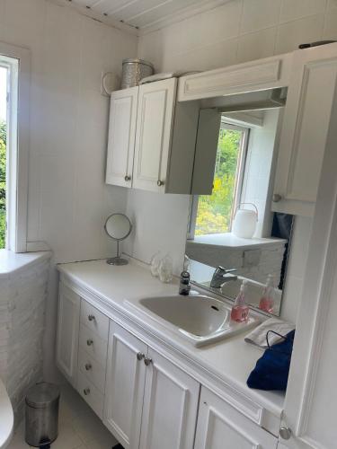 a white kitchen with a sink and a mirror at The Hidden Gem in Ålesund