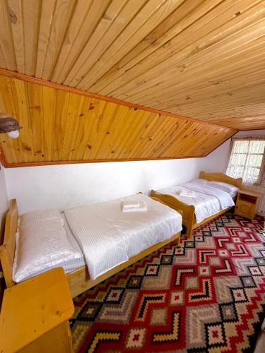two beds in a room with a wooden ceiling at Casa hoinarului in Borca