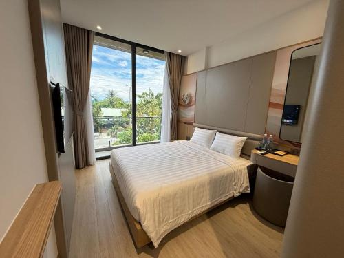 a hotel room with a bed and a large window at Palm Hotel in Tam Kỳ