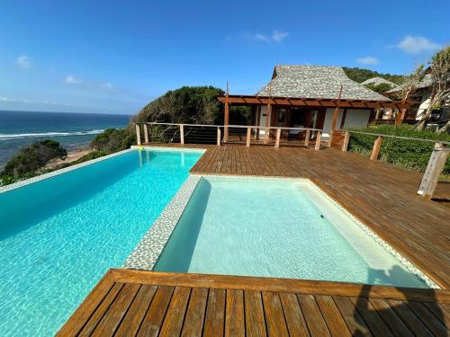 a swimming pool with a wooden deck and the ocean at Makana 7 in Ponta Mamoli