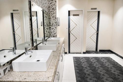 a bathroom with three sinks and two mirrors at Hotel Emience in Chandīgarh