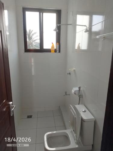 a white bathroom with a toilet and a sink at Chemba's Paradise in Galu