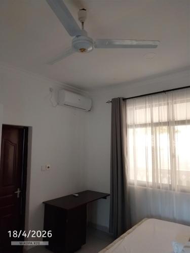 a bedroom with a ceiling fan and a window at Chemba's Paradise in Galu